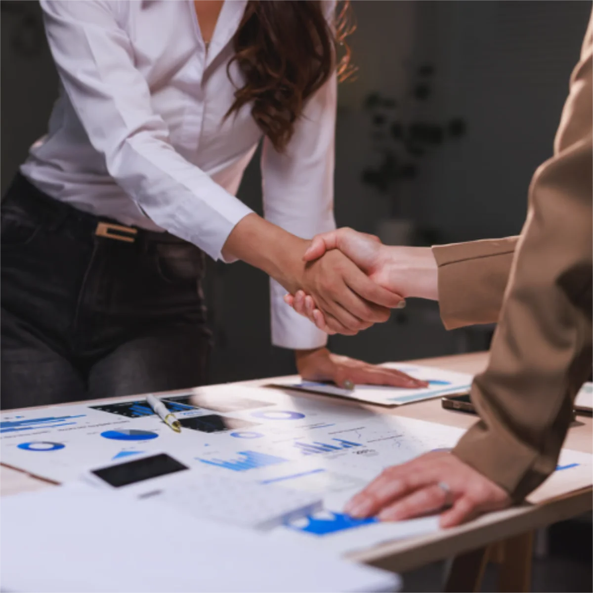 handshake over plans on desk